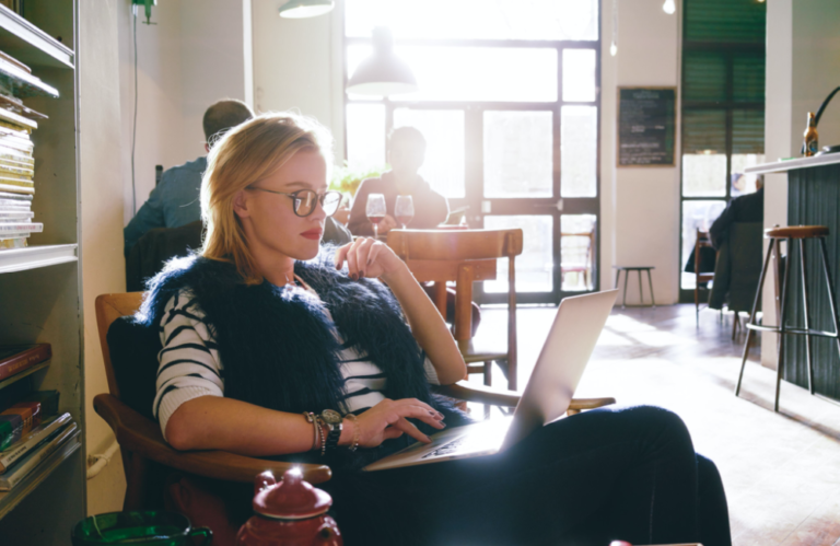 Woman sitting in coffee shop creating content on her laptop computer to illustrate the idea that the future of content marketing is already here