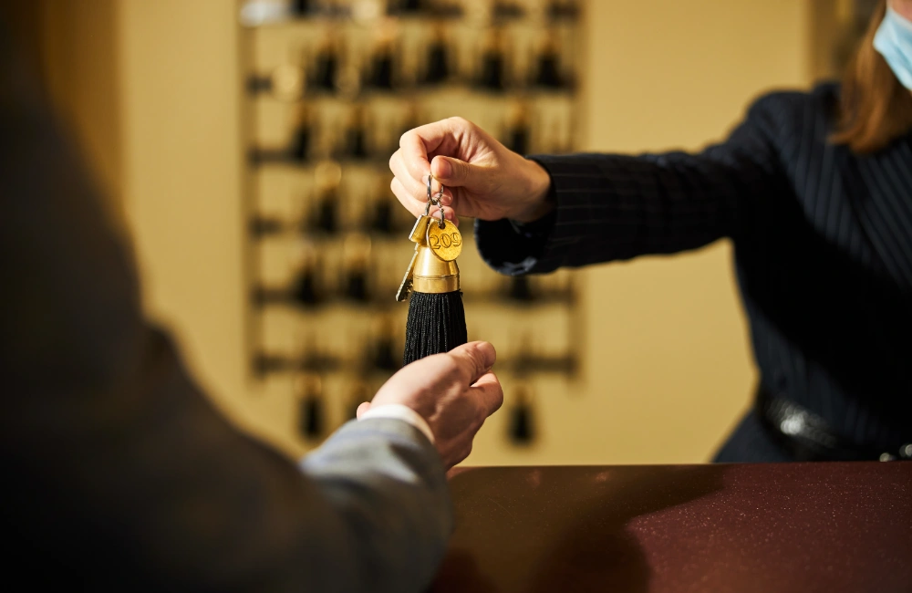 A professional hotel concierge providing personalized service in a modern, minimalist lobby, representing the transition from traditional search engines (SEO) to AI digital assistants and GEO strategy for your brand.