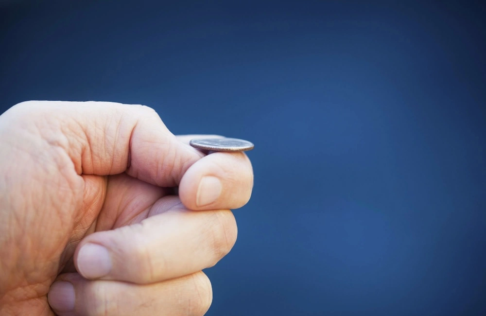 Hand flipping a coin in air to illustrate the issue of AI giving customers different answers to the same prompts.