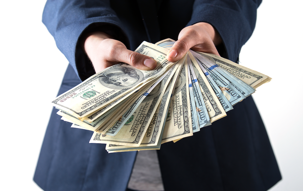 Hands holding a large amount of cash to illustrate the real cost of not owning your customer